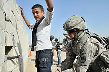 Image 9U.S. Army soldier searches an Iraqi boy, March 2011. (from History of Iraq)