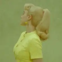 Cover art for "What Was I Made For?": a side-view photo of Billie Eilish in a yellow shirt and with a Barbie-inspired ponytail