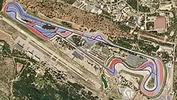 A tarmac course in a semi-rural location lined with large blue-and-red concrete run-off areas