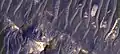 Dark sand on top of light toned material, as seen by HiRISE under the HiWish program.