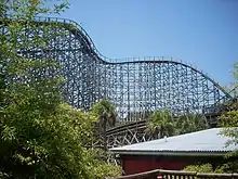 The lift hill of the lion track as it ascends 105.4&nbsp;ft (32.1&nbsp;m) and turns to the right towards the 91.8&nbsp;ft (28.0&nbsp;m) drop. Pieces of track and tree foliage circumnavigate in the foreground.