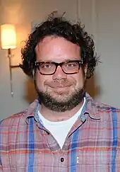 A bearded, smiling, bespectacled Christophe Beck in a plaid shirt