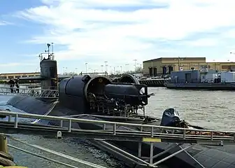 A SEAL Delivery Vehicle (SDV) is loaded aboard the Los Angeles-class fast attack submarine USS&nbsp;Dallas. A Dry Deck Shelter (DDS) is attached to the submarine's forward escape trunk to provide a dry environment for Navy Seals to prepare for special warfare exercises or operations. DDS is the primary supporting craft for the SDV