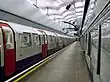 The interior of a building with a rounded ceiling and a white sign on the right wall reading "SEVEN SISTERS" in dark blue letters under a line